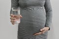 Pregnant woman holding glass water and hand touching belly Royalty Free Stock Photo