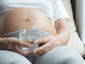 Pregnant woman holding glass of water relaxing at home. Royalty Free Stock Photo