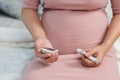 Pregnant woman holding glucose meter and checking blood sugar level by herself at home. gestational diabetes concept Royalty Free Stock Photo