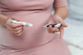 Pregnant woman holding glucose meter and checking blood sugar level by herself at home. gestational diabetes concept Royalty Free Stock Photo