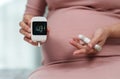 Pregnant woman holding glucose meter and checking blood sugar level by herself at home. gestational diabetes concept Royalty Free Stock Photo