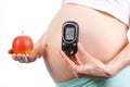 Pregnant woman holding glucose meter and fresh apple, concept of healthy nutrition during pregnancy Royalty Free Stock Photo