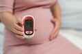 Pregnant woman holding glucose meter with result of measurement sugar high level. gestational diabetes concept