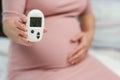 Pregnant woman holding glucose meter with result of measurement sugar high level. gestational diabetes concept