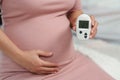 Pregnant woman holding glucose meter with result of measurement sugar high level. gestational diabetes concept