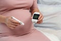 Pregnant woman holding glucose meter with result of measurement sugar high level. gestational diabetes concept