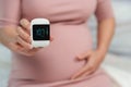 Pregnant woman holding glucose meter with result of measurement sugar level. gestational diabetes concept