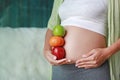 Pregnant woman holding Green-Red Apple and Orange fruit at her tummy. Dieting Concept Royalty Free Stock Photo