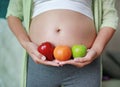 Pregnant woman holding Green-Red Apple and Orange fruit at her tummy Royalty Free Stock Photo