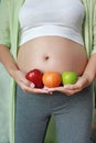 Pregnant woman holding Green-Red Apple and Orange fruit at her tummy Royalty Free Stock Photo