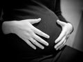 pregnant woman holding hands on her baby bump Royalty Free Stock Photo