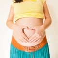 Pregnant woman holding hands on her belly making a heart symbol. Maternity concept. Royalty Free Stock Photo