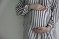 A pregnant woman holding her baby bump stood against a plain background Royalty Free Stock Photo