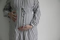 A pregnant woman holding her baby bump stood against a plain background Royalty Free Stock Photo