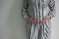 A pregnant woman holding her baby bump stood against a plain background Royalty Free Stock Photo