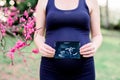 Pregnant Woman Holding Her Baby`s Ultrasound Photo with Spring Flowers Royalty Free Stock Photo