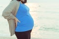 Pregnant woman holding her belly on the beach with copy space in Royalty Free Stock Photo