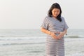 Pregnant woman holding her belly on the beach with copy space. Royalty Free Stock Photo