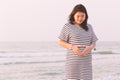 Pregnant woman holding her belly on the beach with copy space in Royalty Free Stock Photo