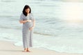 Pregnant woman holding her belly on the beach. Royalty Free Stock Photo