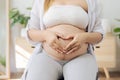 Pregnant woman holding her hand in the shape of a heart symbolizes of love at her belly. Royalty Free Stock Photo