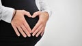 Pregnant Woman holding her hands in a heart shape on her baby bump. Pregnant Belly with fingers Heart symbol. Maternity Royalty Free Stock Photo