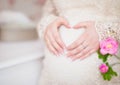 Pregnant woman holding her hands in a heart shape on her belly Royalty Free Stock Photo