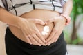 Pregnant Woman holding her hands in heart shape Pregnant Belly with fingers Heart symbol. Royalty Free Stock Photo