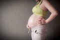 Pregnant woman is holding her stomach by her hand