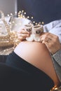 Pregnant woman holding little baby socks near her belly. Expectant mother preparing wicker basket with ultrasound image and stuff Royalty Free Stock Photo