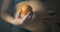 Pregnant woman holding Orange fruit at her tummy. Royalty Free Stock Photo