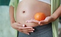 Pregnant woman holding Orange fruit at her tummy Royalty Free Stock Photo