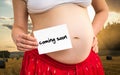 Pregnant woman holding paper with inscription: coming soon Royalty Free Stock Photo