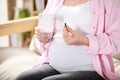 Pregnant woman holding pill and glass of water at home, closeup Royalty Free Stock Photo