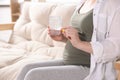 Pregnant woman holding pill and glass with water at home, closeup Royalty Free Stock Photo