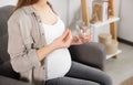 Pregnant woman holding pill and glass with water at home, closeup Royalty Free Stock Photo