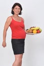 Pregnant woman holding a plate of grup of fruit on white background