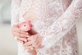 Pregnant woman holding ranunculus flower above belly