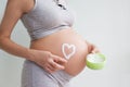 Pregnant woman holding red heart and hand on her belly, symbol of new life, concept of expecting for baby and extending family Royalty Free Stock Photo