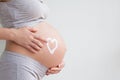 Pregnant woman holding red heart and hand on her belly, symbol of new life, concept of expecting for baby and extending family Royalty Free Stock Photo