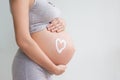 Pregnant woman holding red heart and hand on her belly, symbol of new life, concept of expecting for baby and extending family Royalty Free Stock Photo