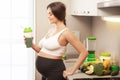 Pregnant woman holding shaker with a green protein cocktail