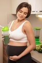 Pregnant woman holding shaker with a green protein cocktail