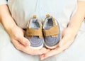 Pregnant woman holding small baby shoes in hands. Maternity prenatal care and woman pregnancy concept Royalty Free Stock Photo