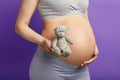 Pregnant woman holding toy teddy bear, near her big belly, close up Royalty Free Stock Photo