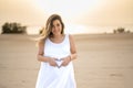 Pregnant woman holding tummy and showing heart shape with hands at beach. Royalty Free Stock Photo