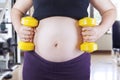 Pregnant woman holding two dumbbells Royalty Free Stock Photo