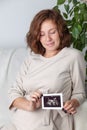 Pregnant woman holding ultrasound image. Concept of pregnancy, health care, gynecology, medicine. Young mother waiting Royalty Free Stock Photo