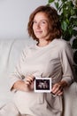 Pregnant woman holding ultrasound image. Concept of pregnancy, health care, gynecology, medicine. Young mother waiting Royalty Free Stock Photo