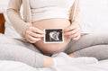 Pregnant woman holding ultrasound photo near belly Royalty Free Stock Photo